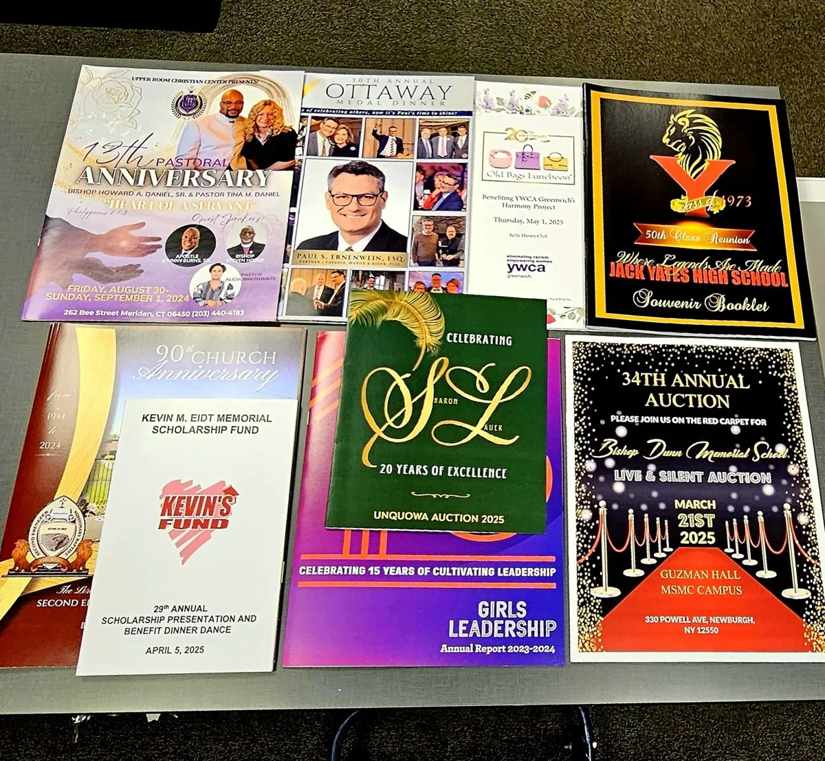 Seven saddle-stitched booklets and programs laid out on a table