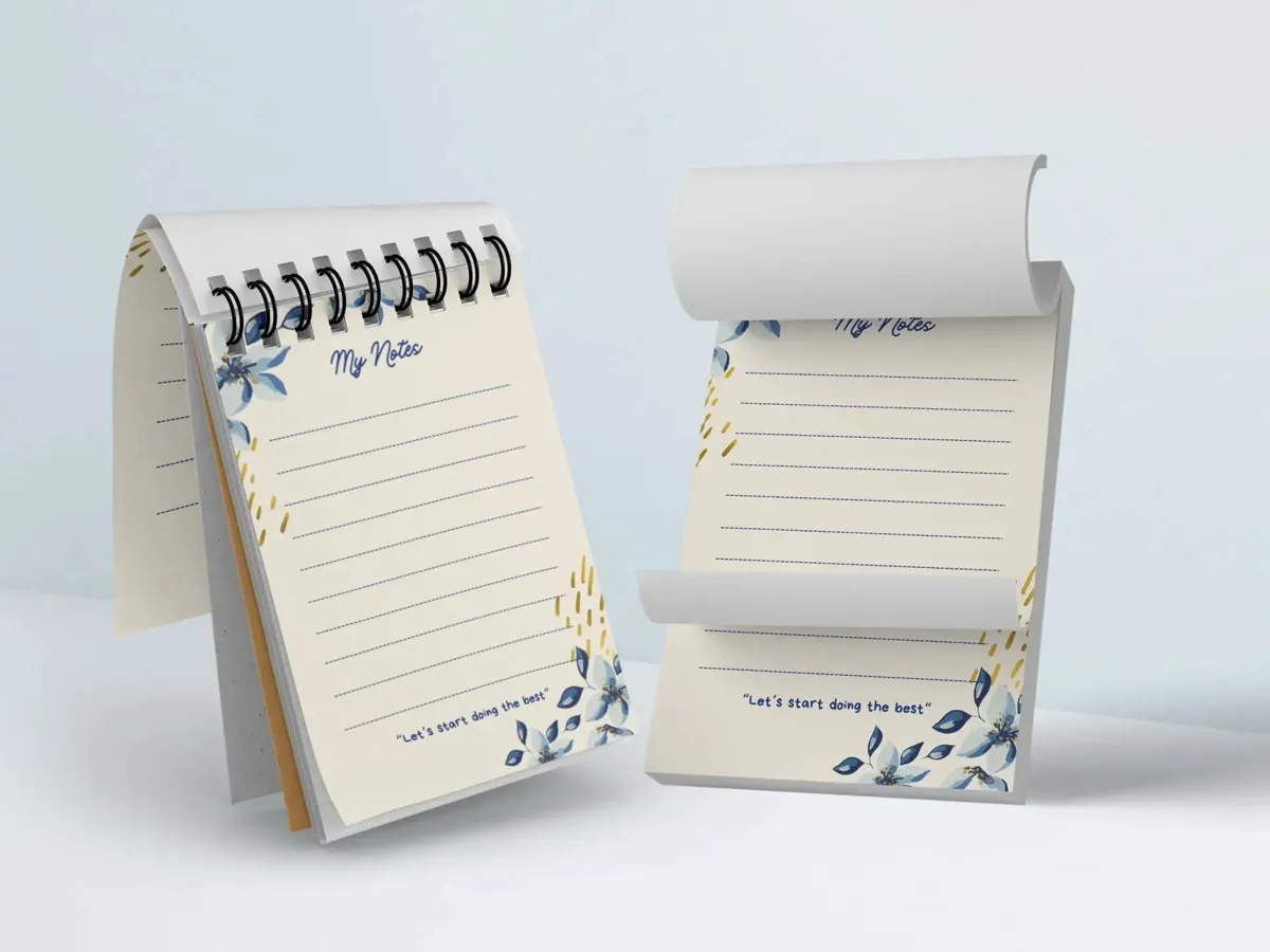 Two lined notepads with a blue floral design, one spiral bound and one glued at the top