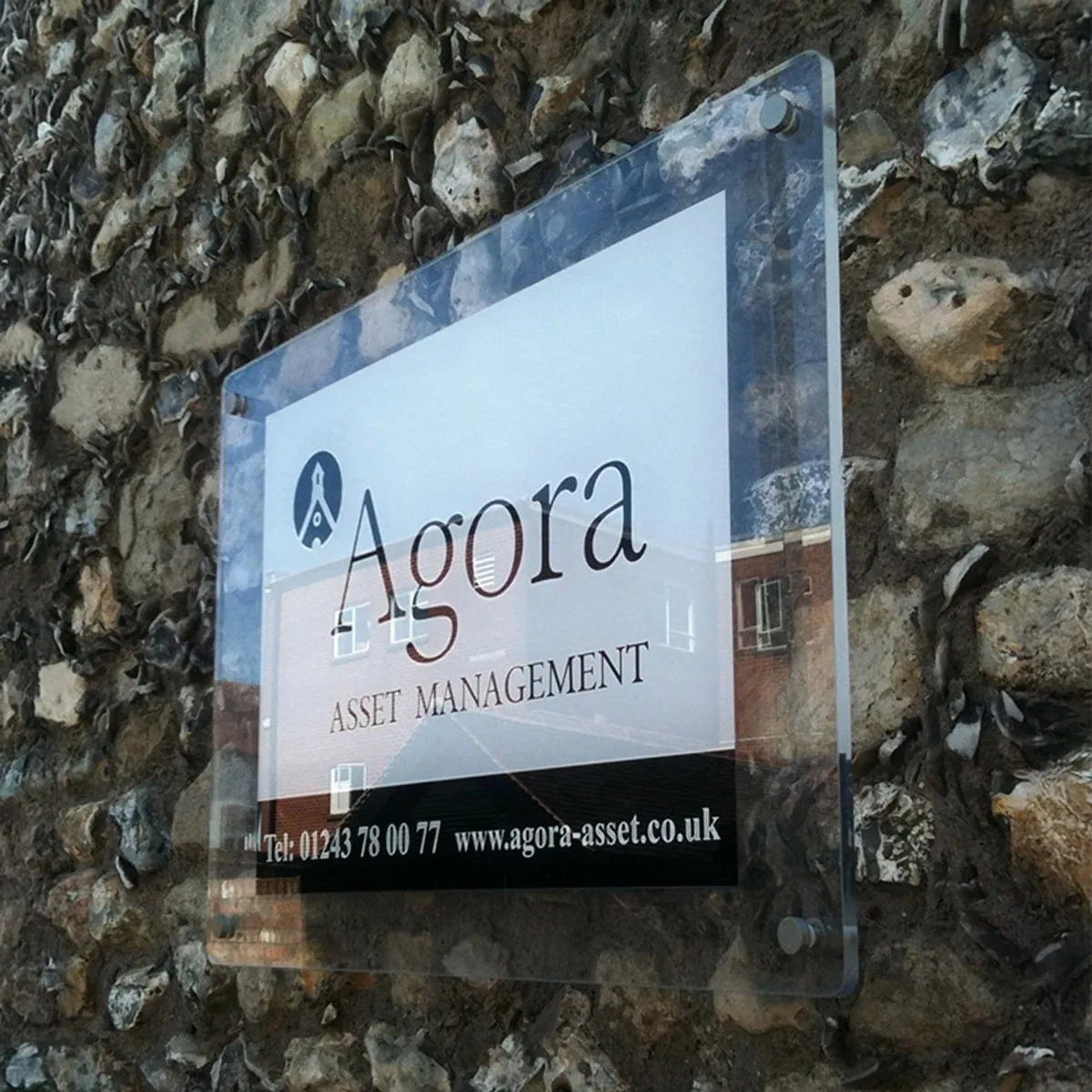 An acrylic business sign on stand-off mounts fixed to a stone wall